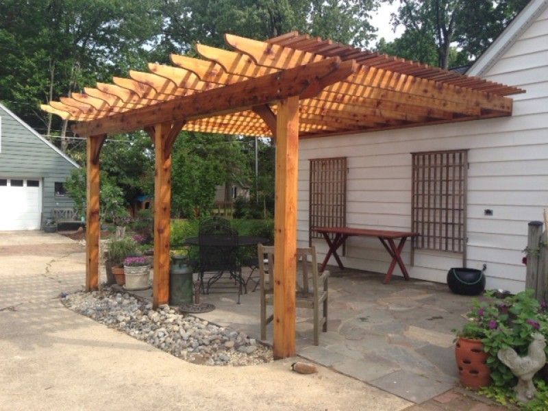 Wooden pergola attached to a house, shading a patio with seating.
