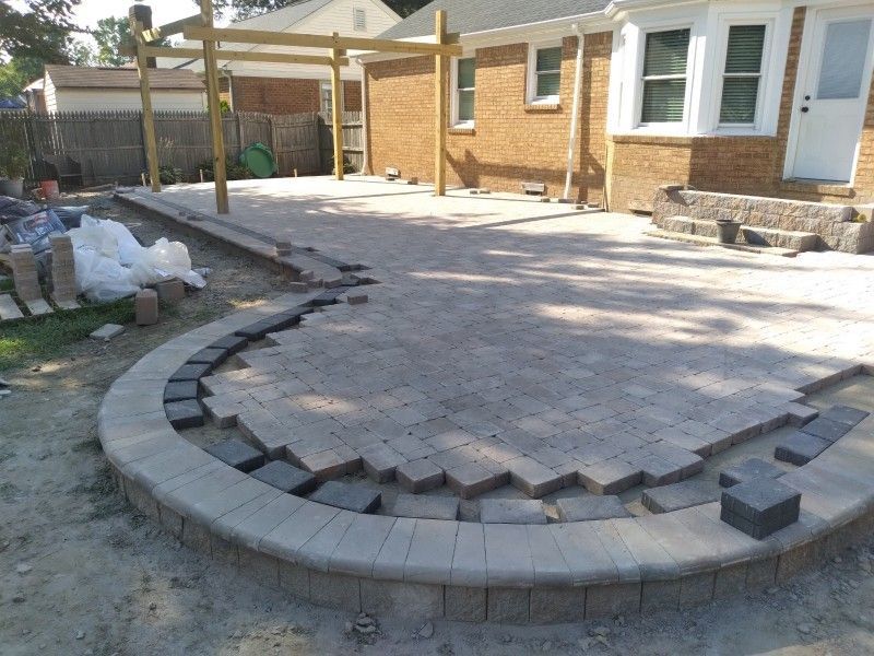 Backyard patio under construction; pavers being laid, curved border.