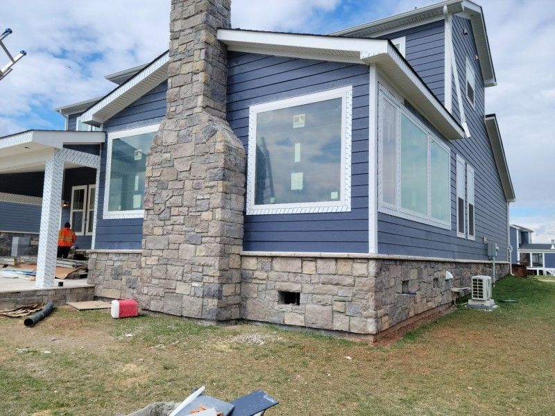 Blue house with stone accents and large windows under construction.