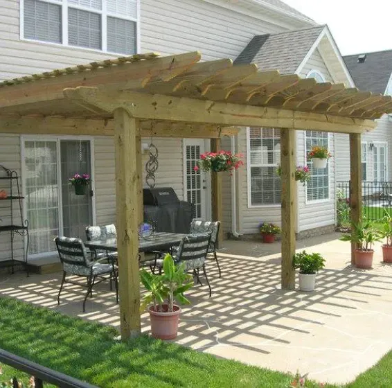 Wooden pergola over patio with outdoor furniture and hanging flower baskets.