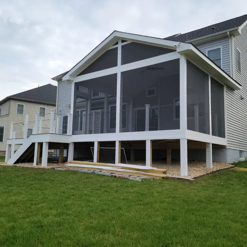 Screened-in porch with white trim, attached to a two-story house, overlooking a grassy yard.