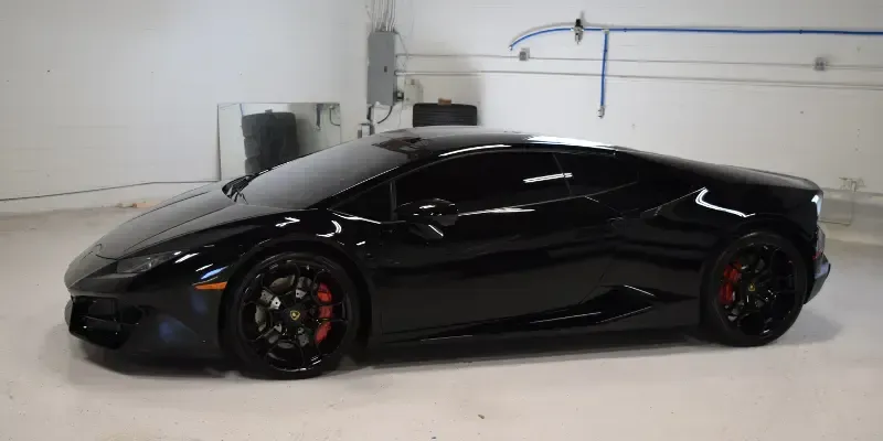 A black lamborghini huracan is parked in a garage.