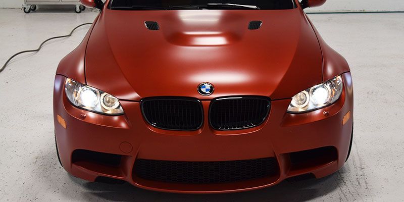 A red bmw m3 is parked in a garage.