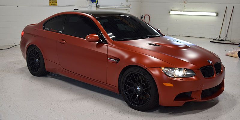 A red bmw m3 is parked in a garage.