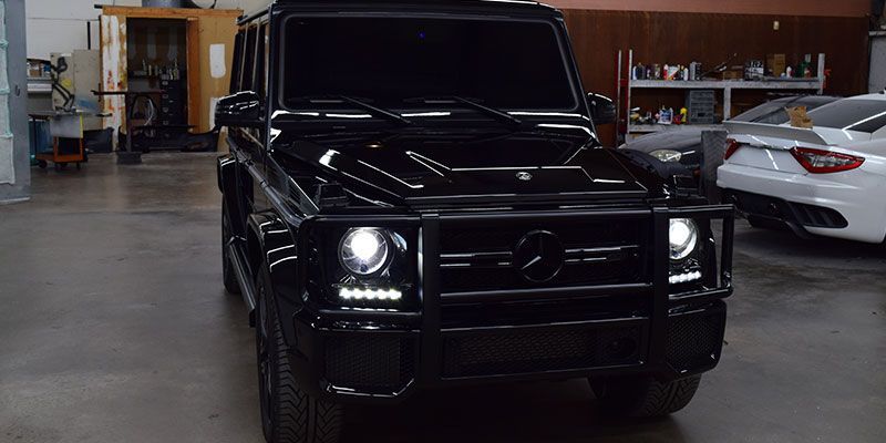 A black mercedes benz g63 is parked in a garage.