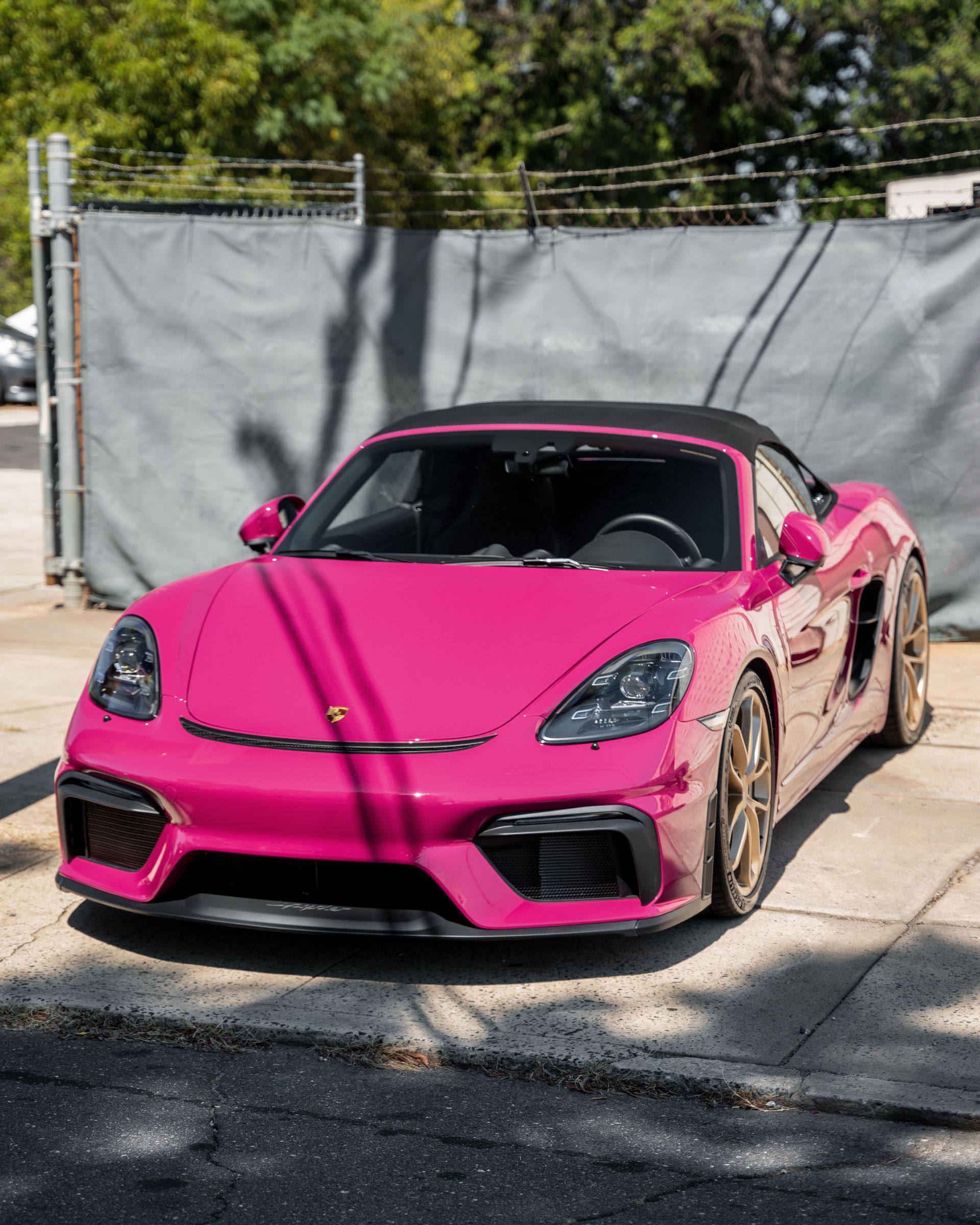 A pink sports car is parked on the side of the road.