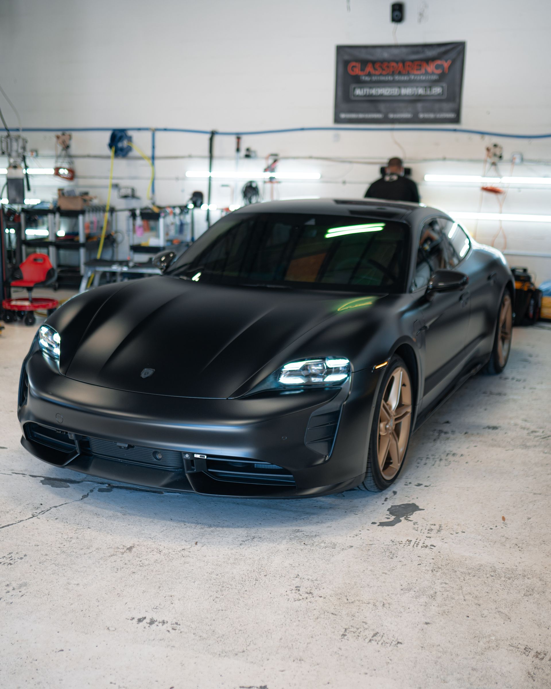 A black porsche taycan is parked in a garage