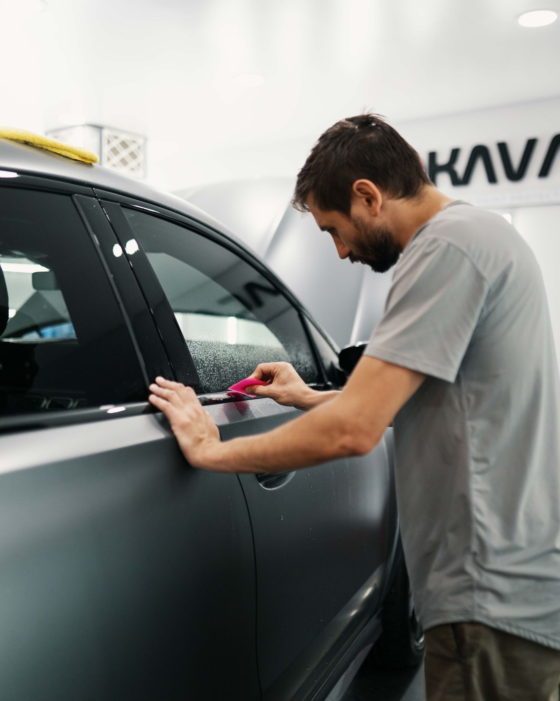 A man in a grey shirt is working on a car
