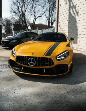 A yellow mercedes amg gt r is parked in front of a building.