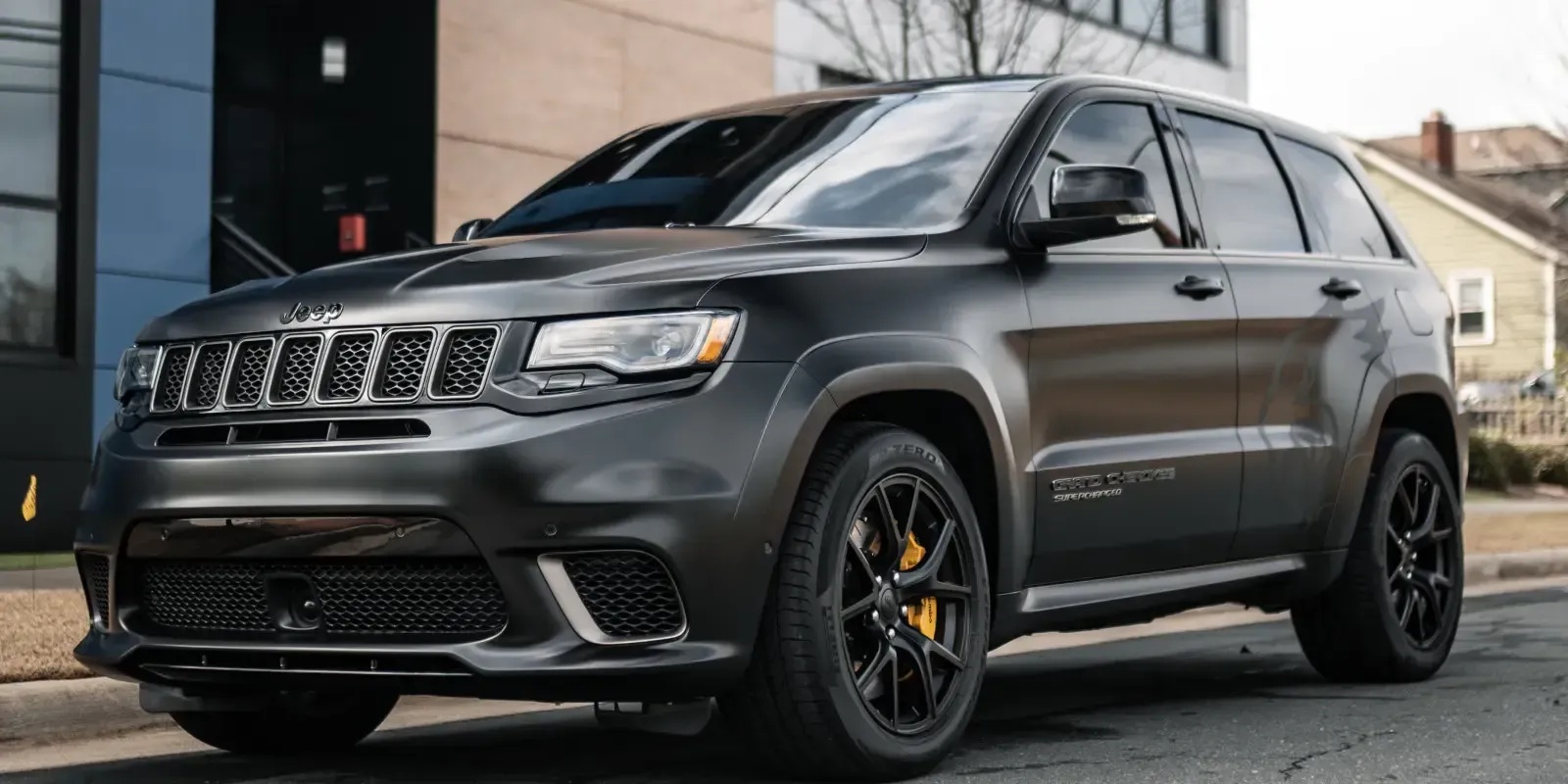 A black jeep grand cherokee is parked in front of a building.