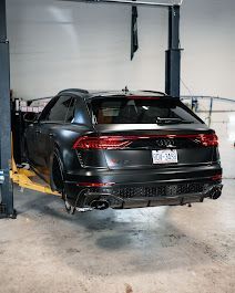 A black audi q8 is parked on a lift in a garage.