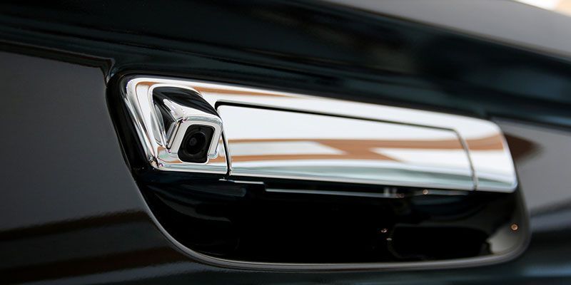 A close up of a car door handle with a camera on it.