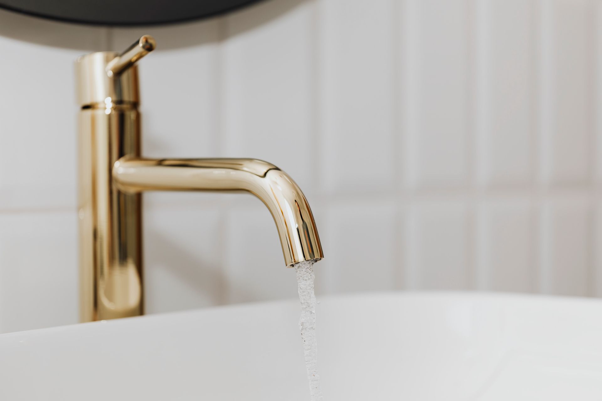 Gold Faucet Pouring Water Into a White Sink, White Tiled Wall — Hot Water Specialist Forster In Forster, NSW