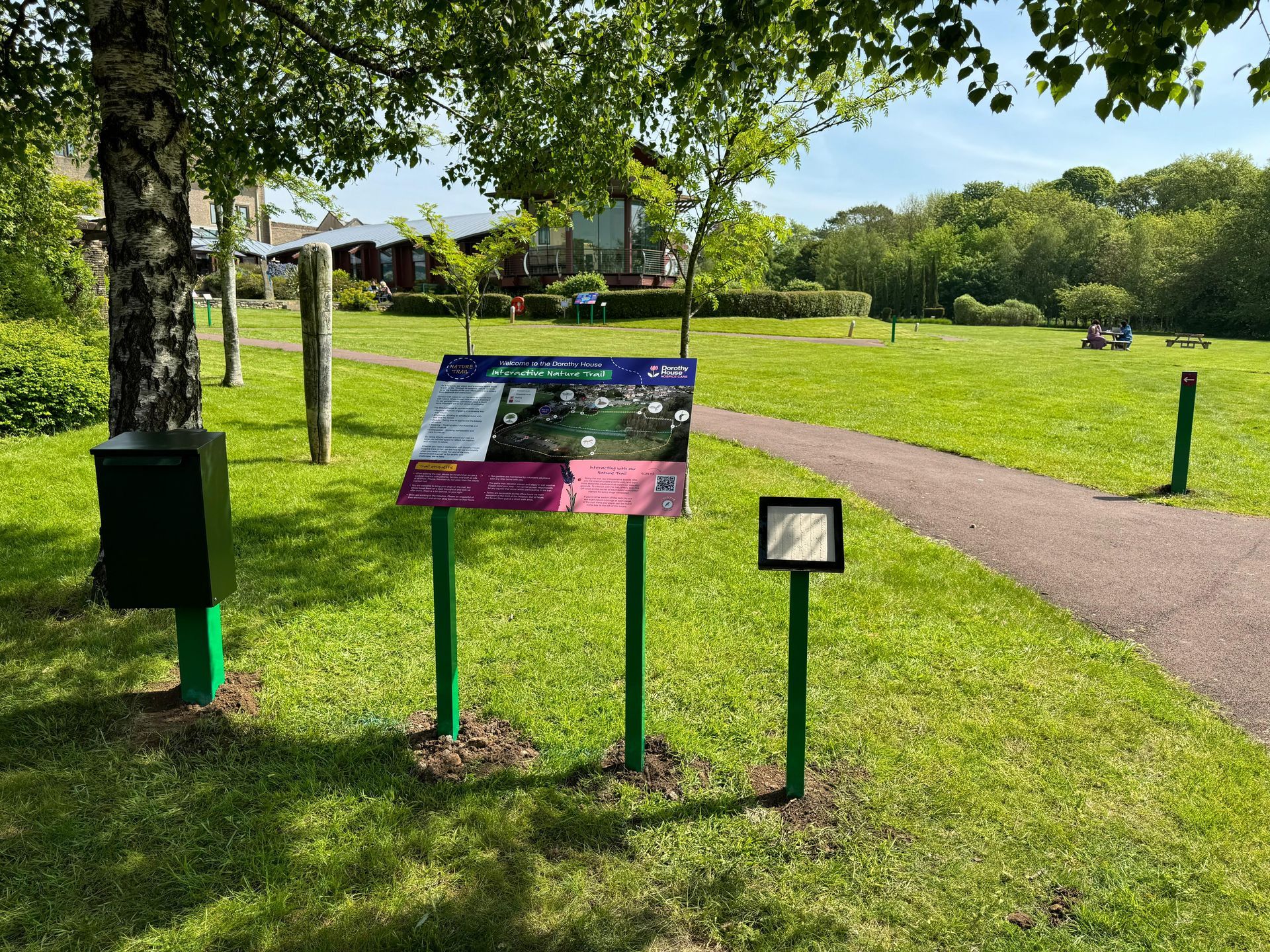 A park with a sign in the middle of it and a path.
