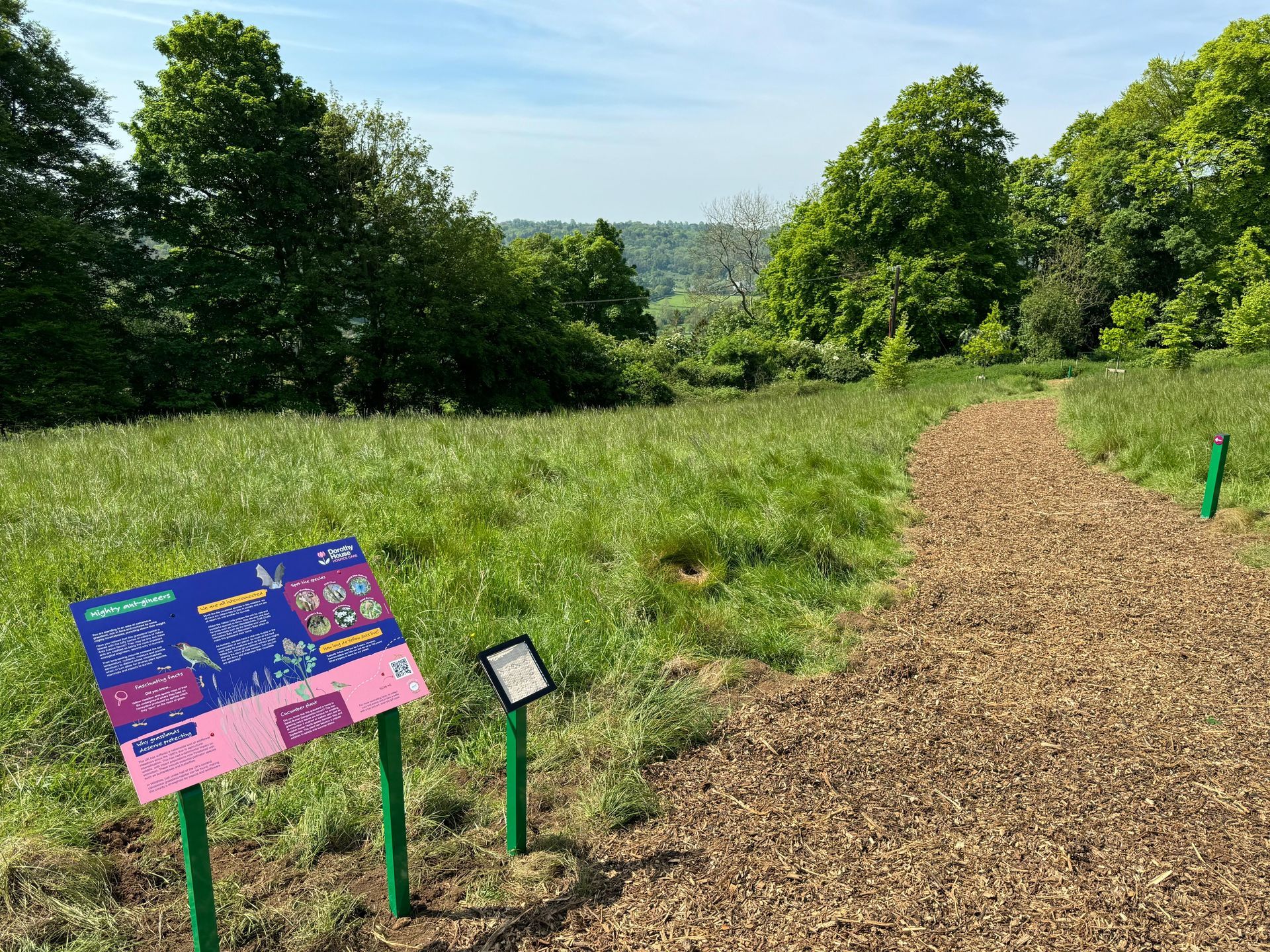 A sign on the side of a path in a field.