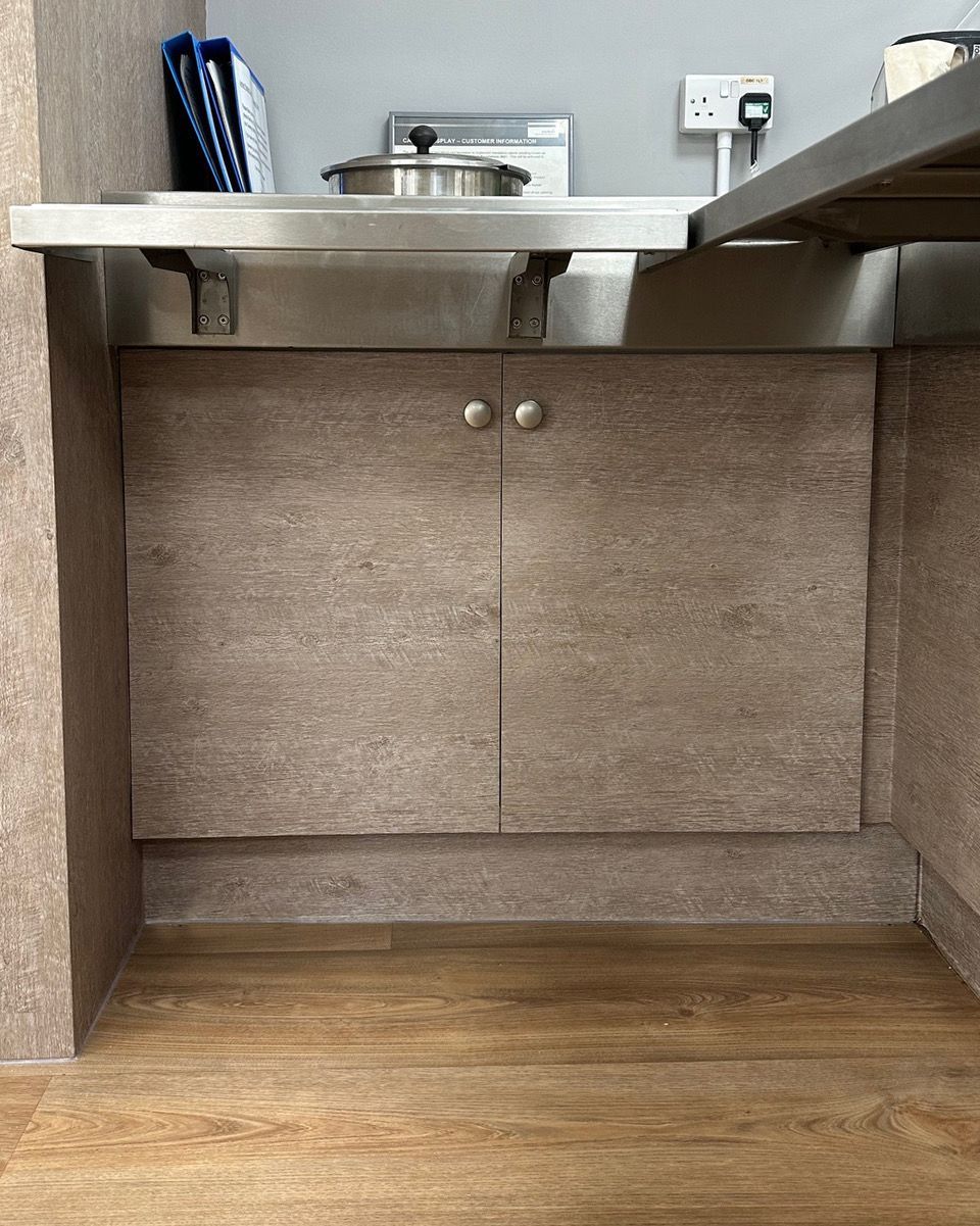 A kitchen with a sink and cabinets and a wooden floor.