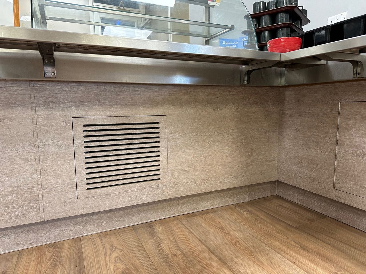 A kitchen with a stainless steel shelf and a wooden floor.