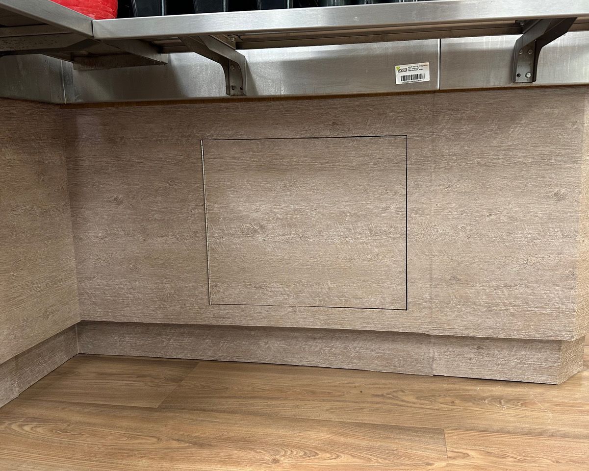 An empty room with a wooden floor and a stainless steel shelf.