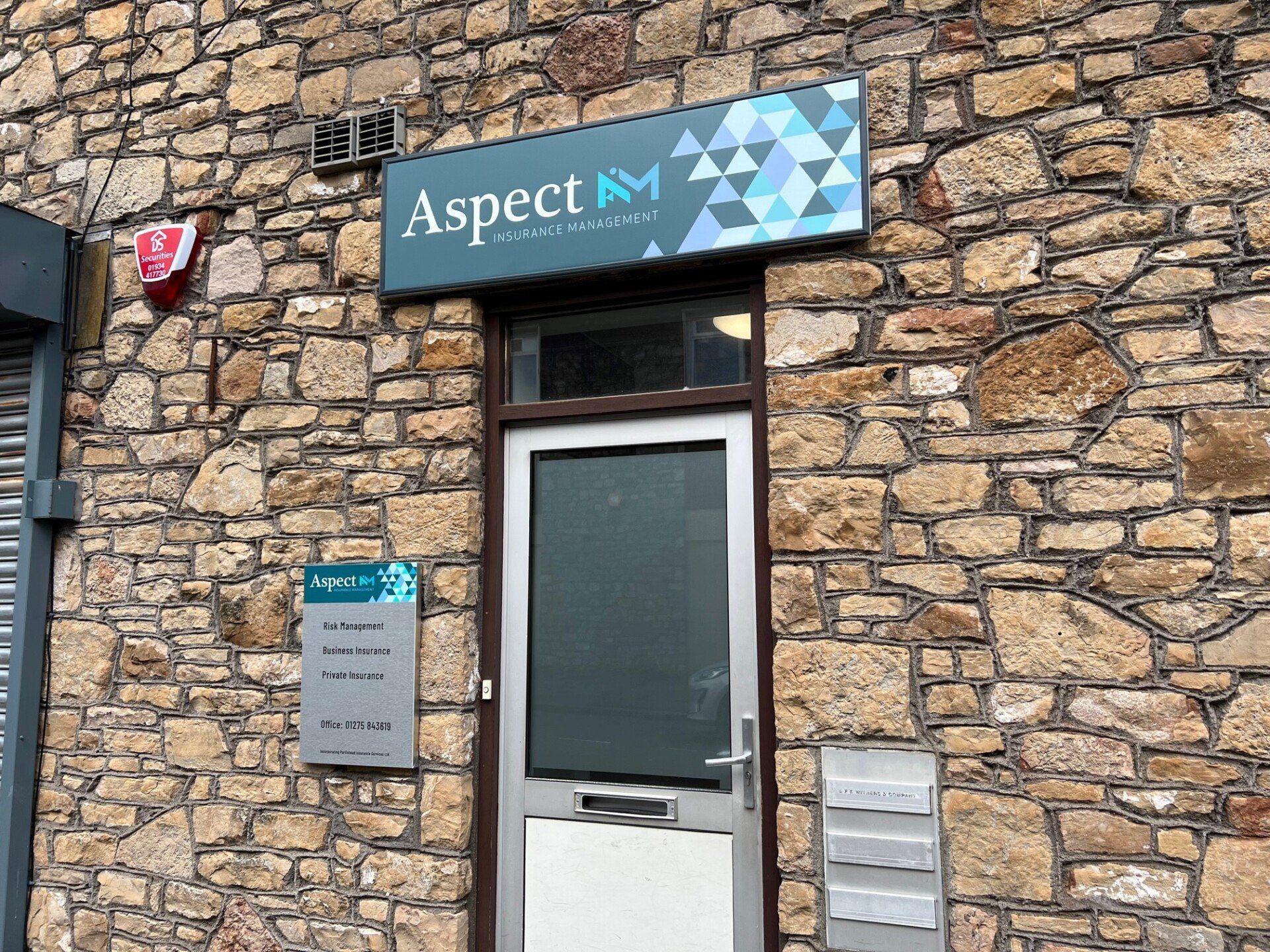 The front door of a stone building with a sign above it that says aspect.