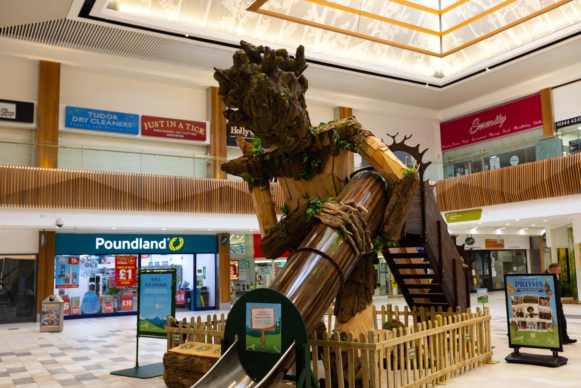 A large statue of a tree is in the middle of a shopping mall.