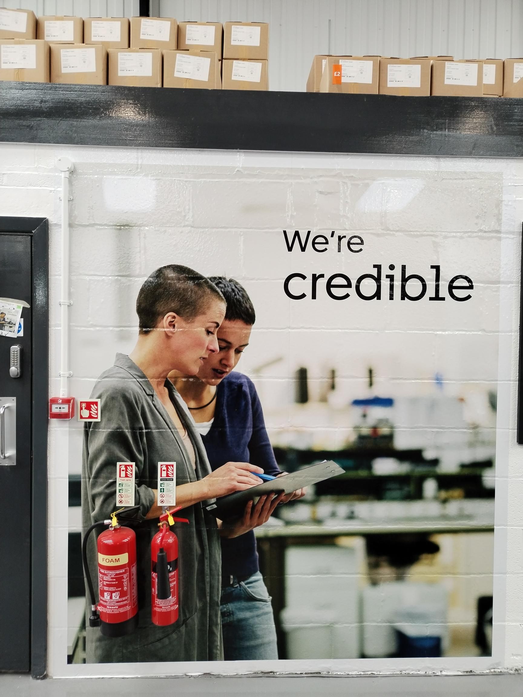 Two women standing next to each other in front of a sign that says we 're credibile