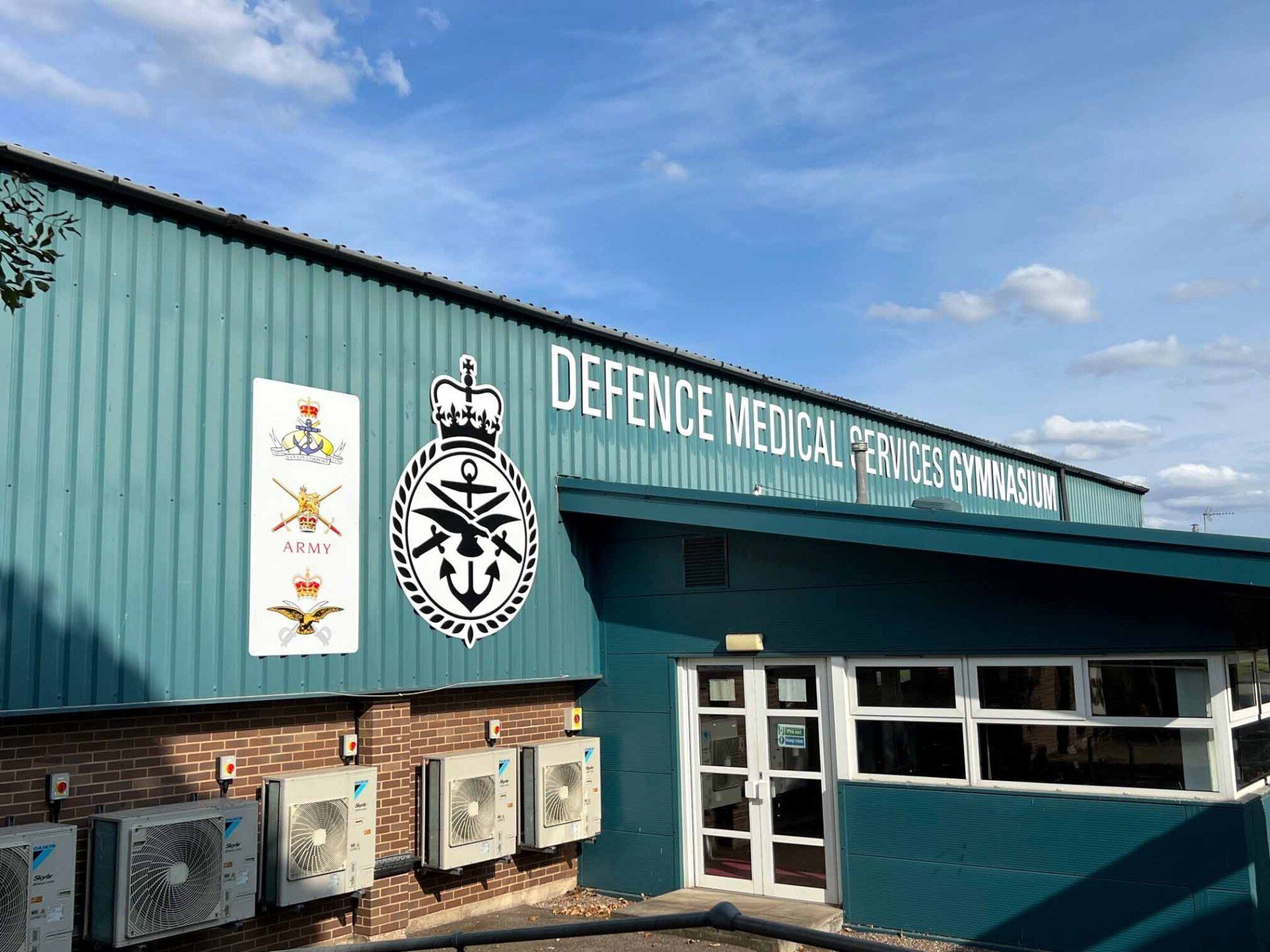 A green building with a sign on it that says `` defence medical service gymnasium ''.