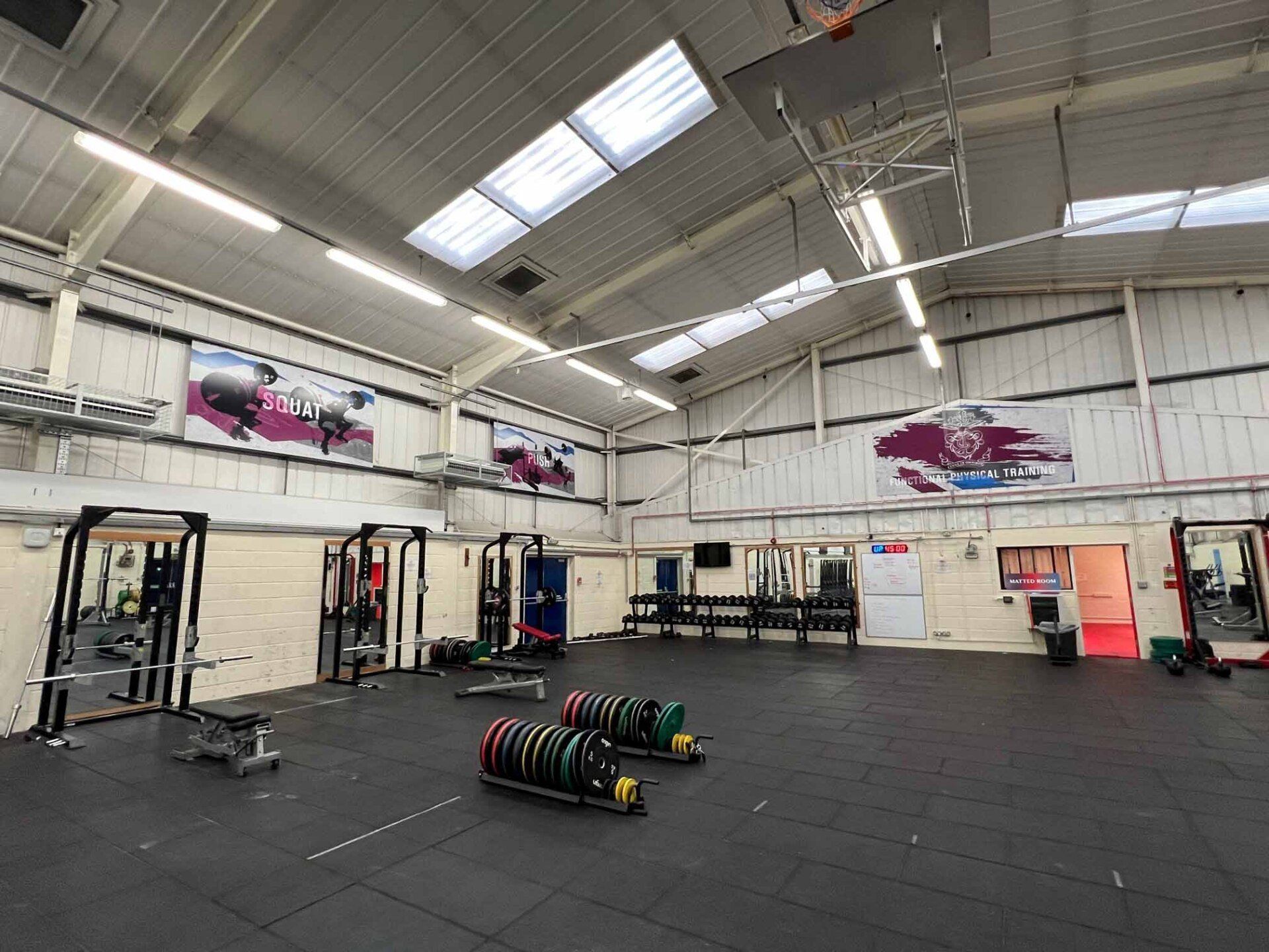 A large gym with a lot of equipment and a basketball hoop.