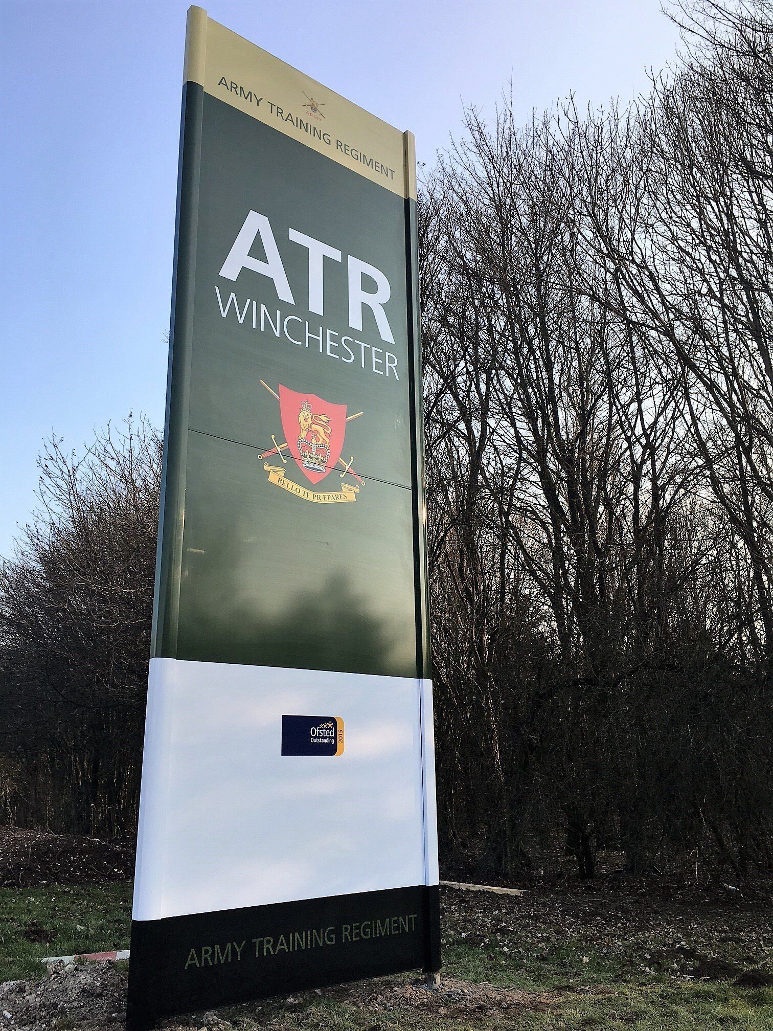 A large green and white sign that says atr winchester is surrounded by trees.