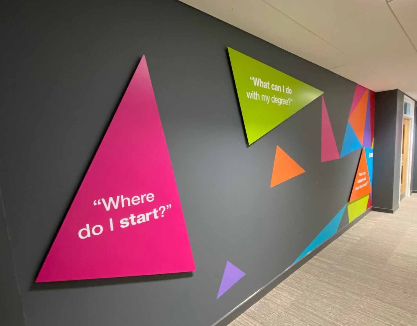 A hallway with colorful triangles and a sign that says