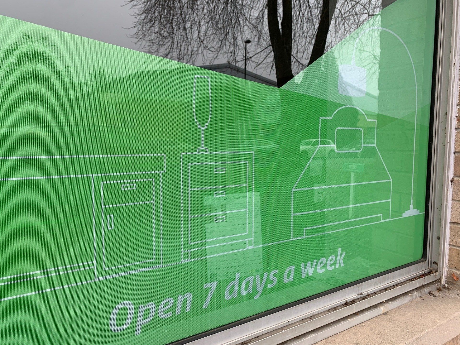 A window with a green sign that says `` open 7 days a week ''.