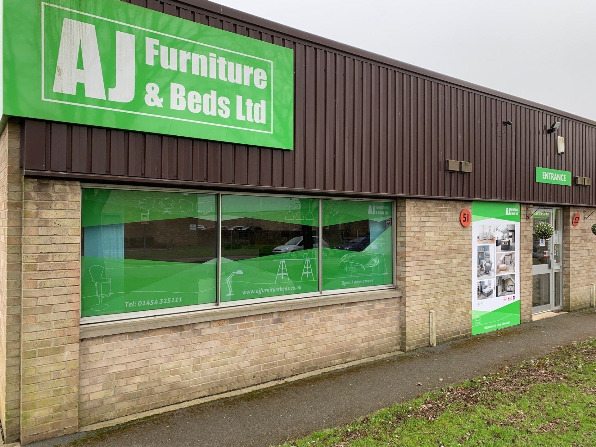 A large building with a green sign that says aj furniture & beds ltd.