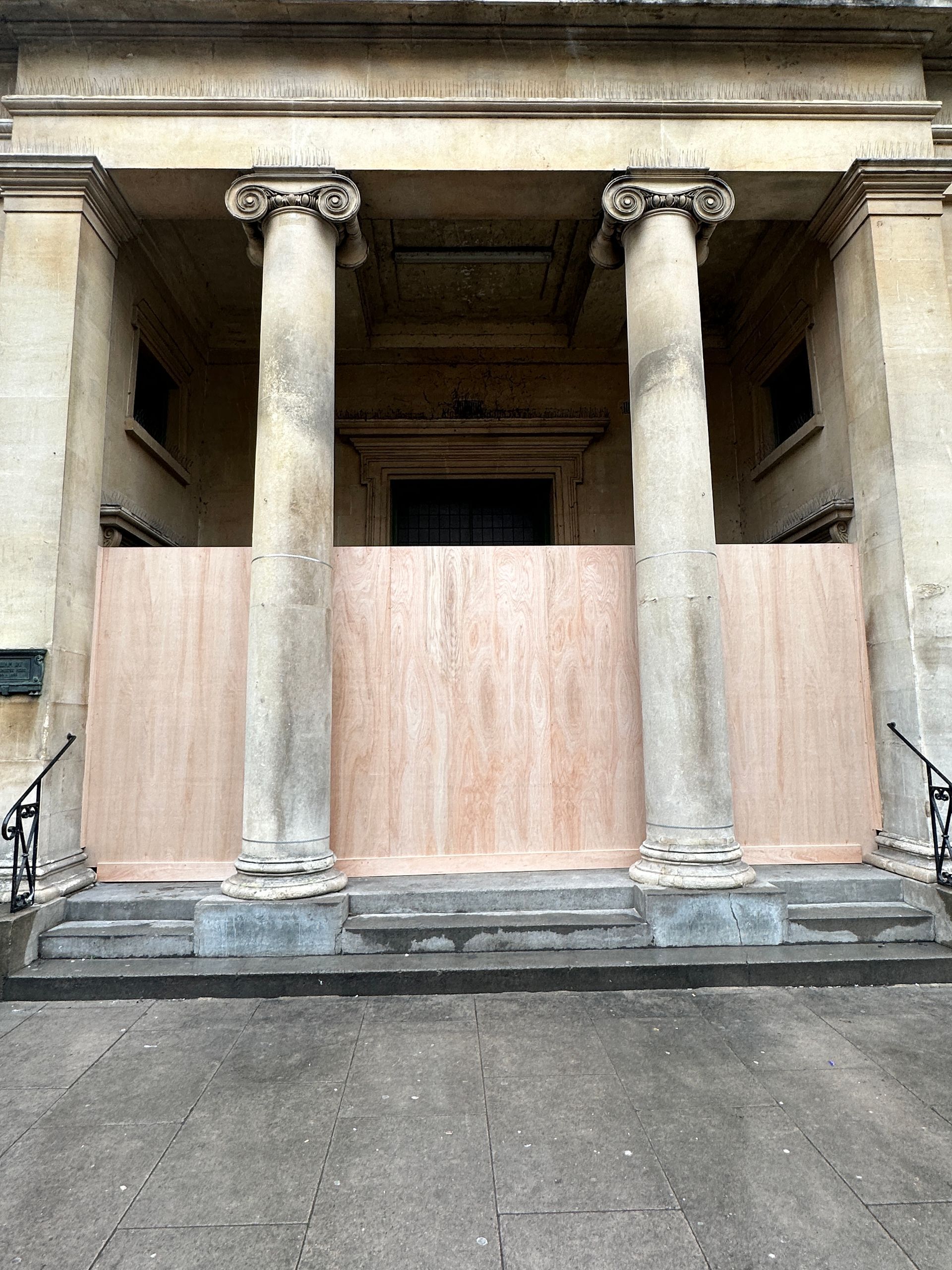 The front of a building with a wooden barrier between the columns.