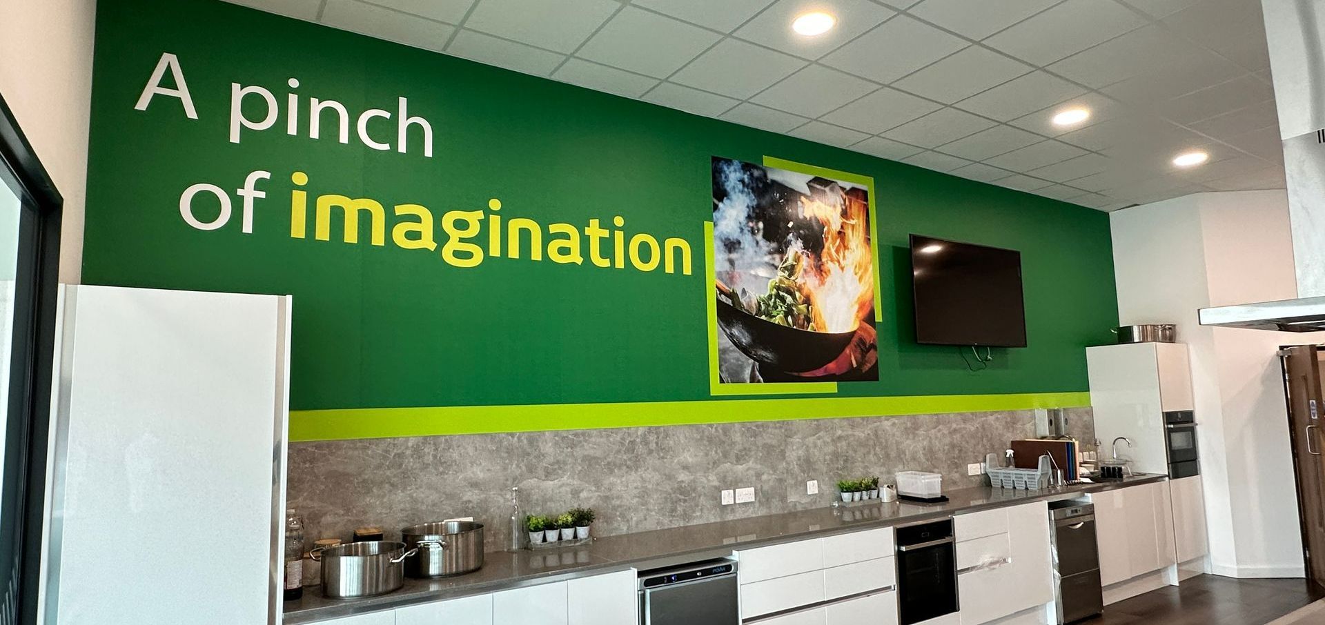 A kitchen with a green wall that says `` a pinch of imagination ''.