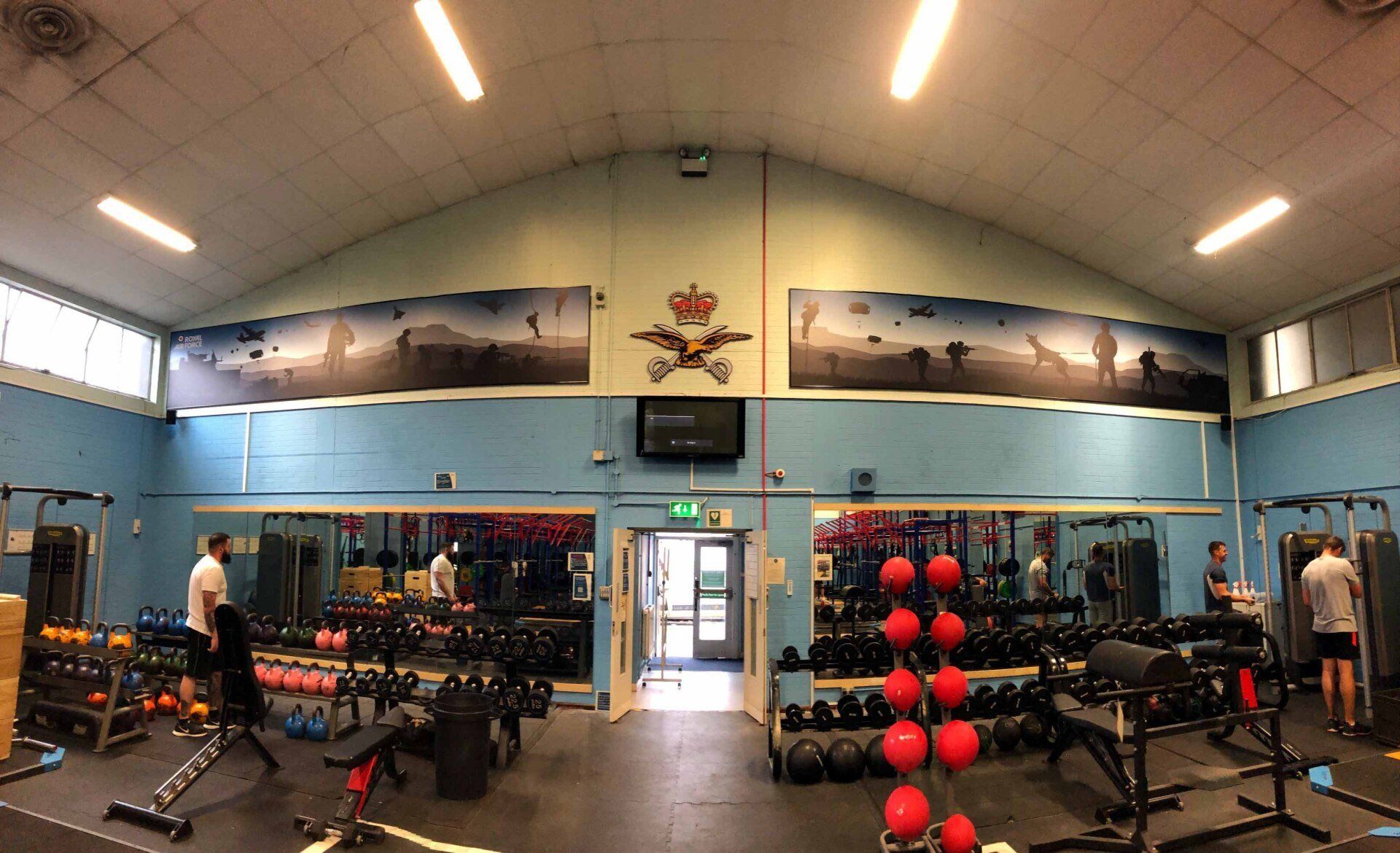 A large gym with a lot of equipment and a large mirror.