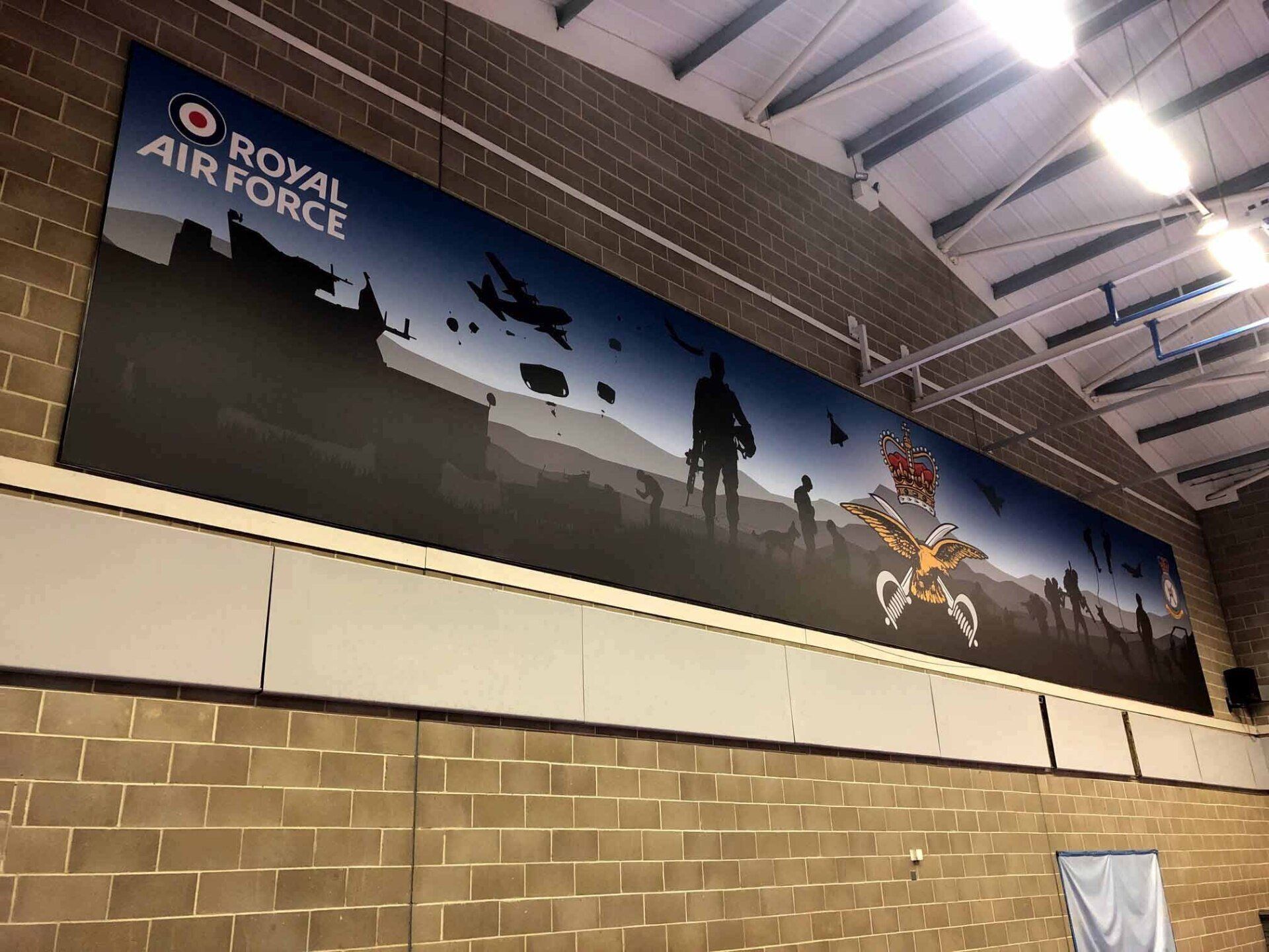 A large mural for the royal air force hangs on a brick wall