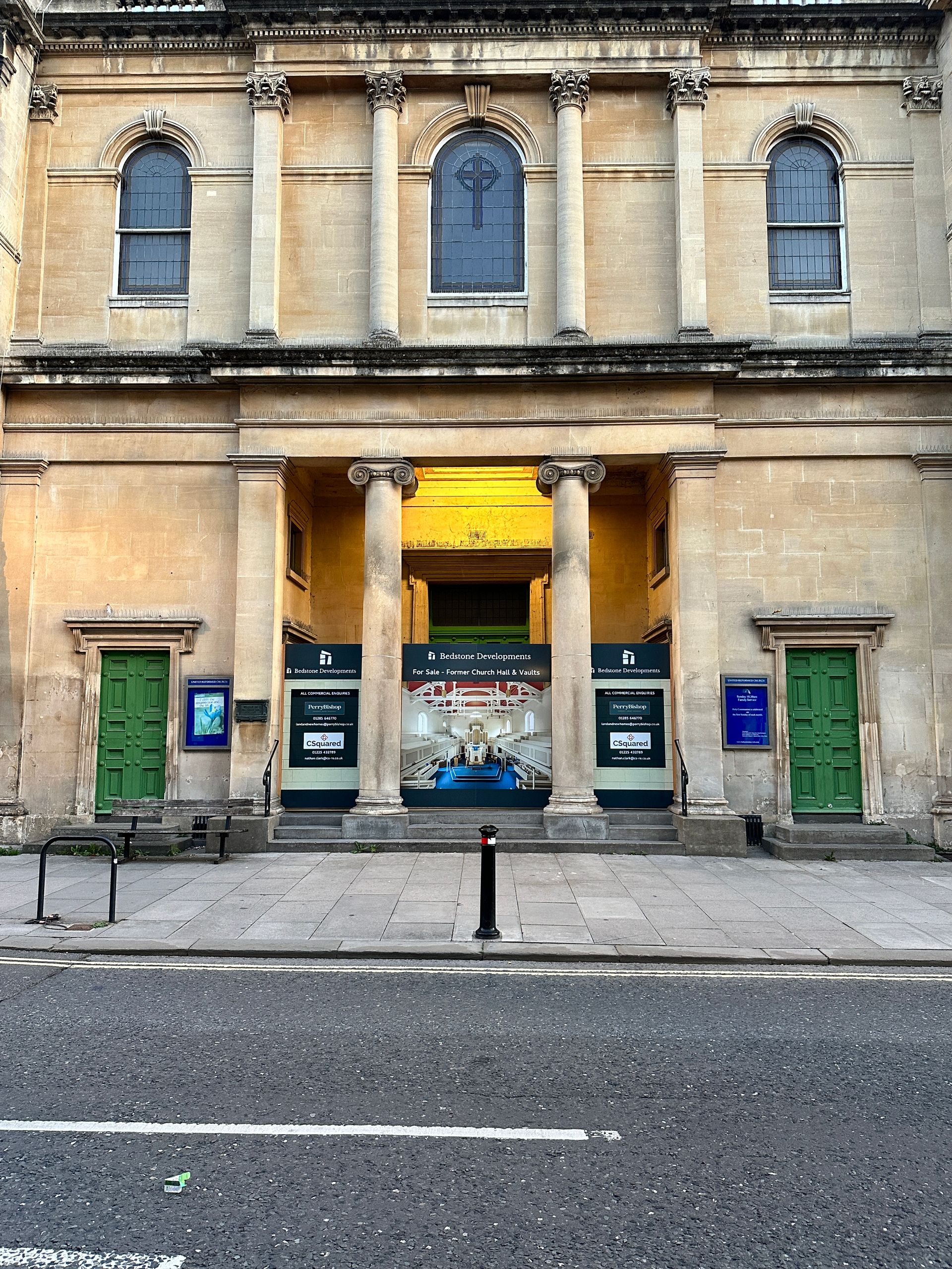 The front of a building with green doors and columns