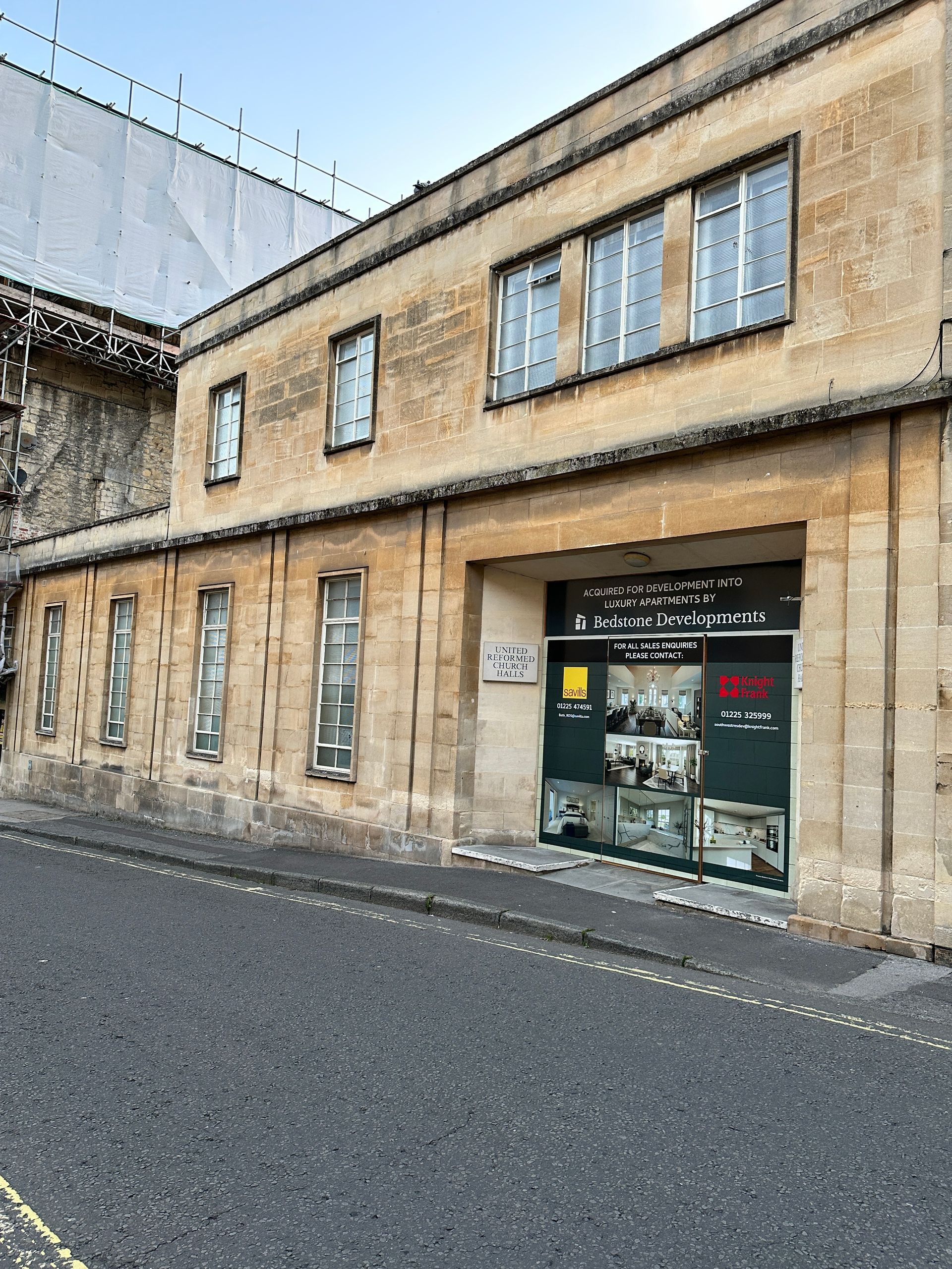 A large building with a lot of windows is on the side of a street.