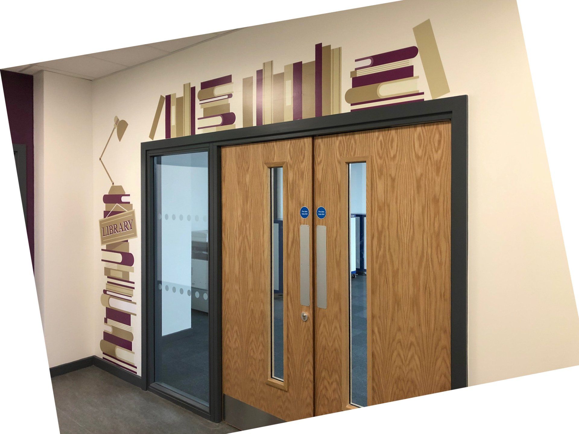 A hallway with wooden doors and a mural of books on the wall.