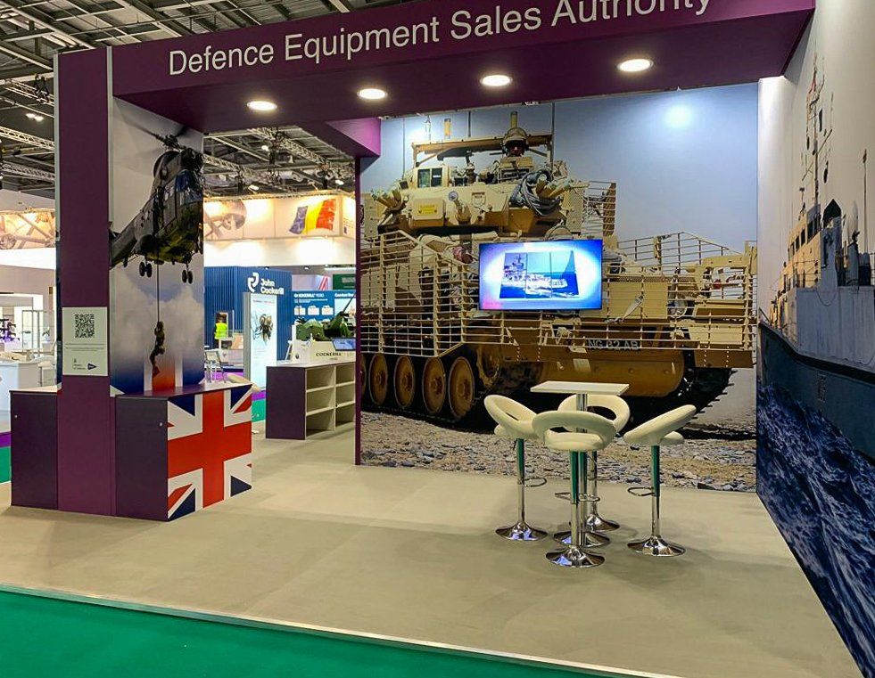 A defence equipment sales authority booth with a picture of a tank on the wall.