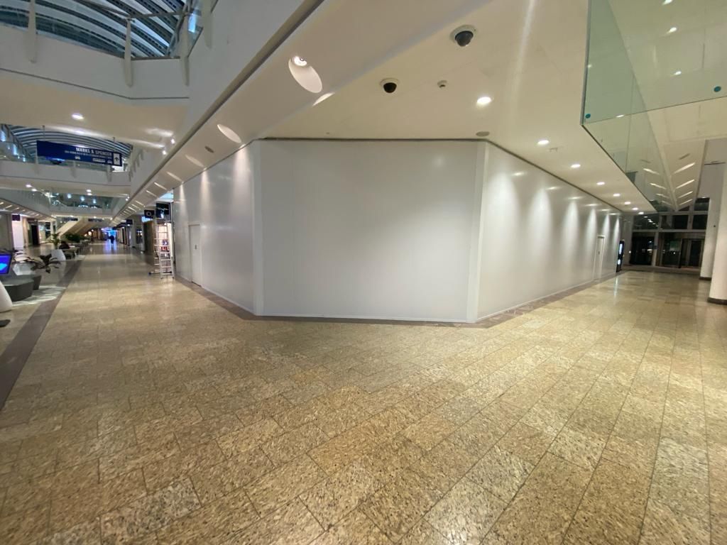 An empty mall with a white wall and a tiled floor.