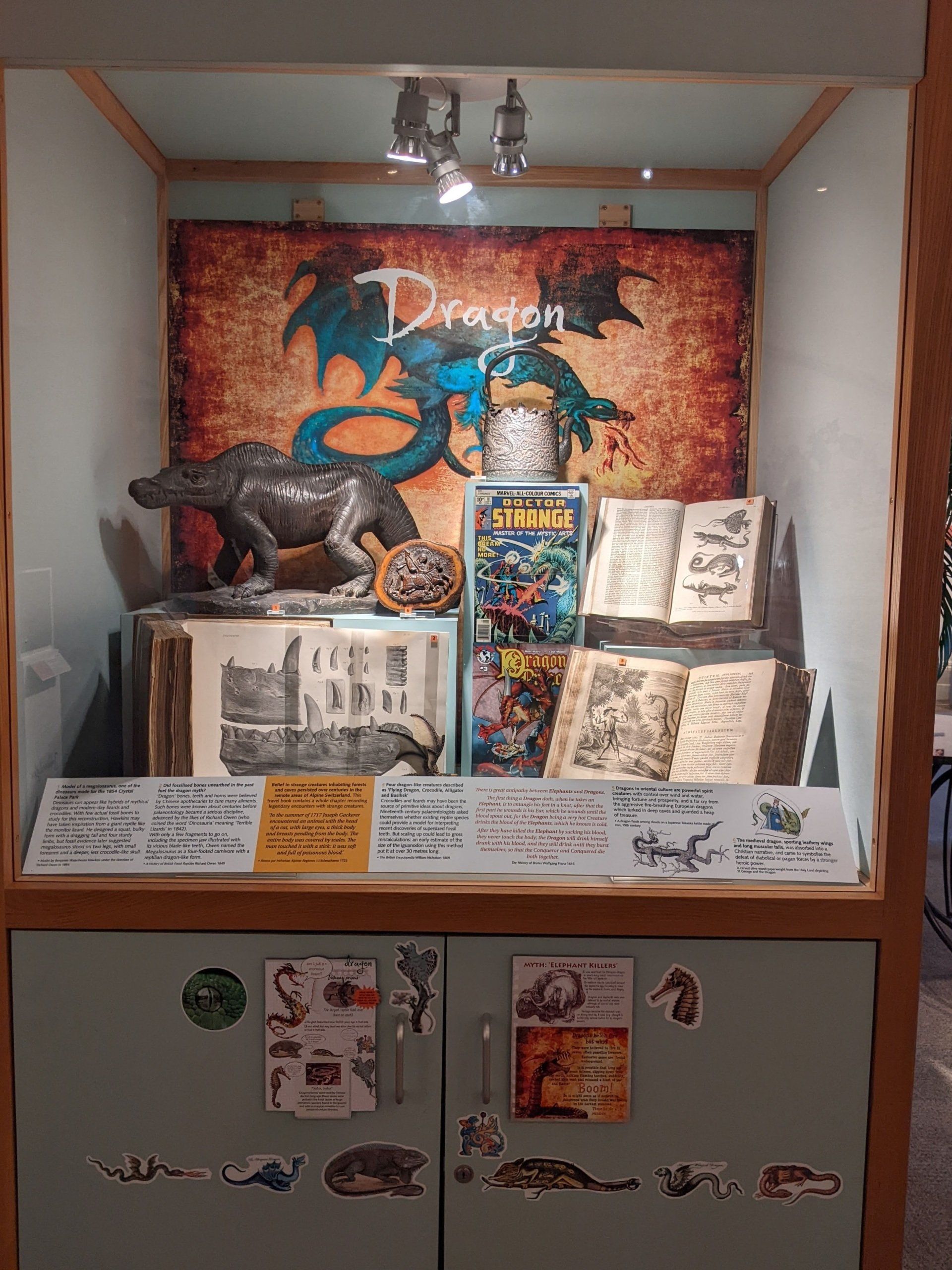A display case with a dragon statue and books on it