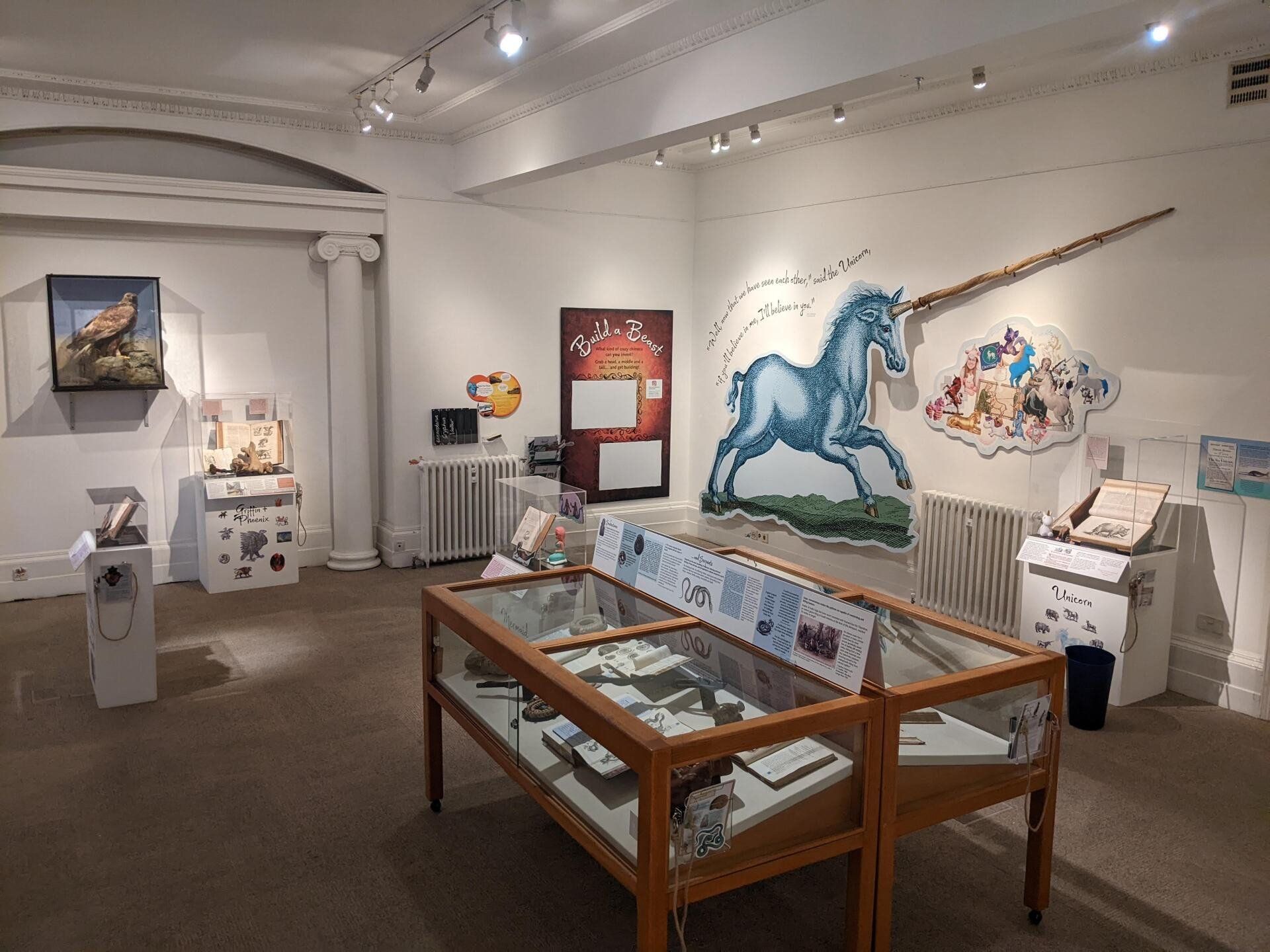 A room with a table and a painting of a unicorn on the wall.