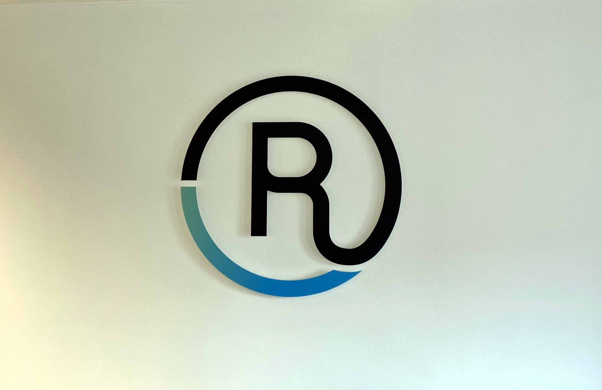The letter r is in a blue circle on a white wall