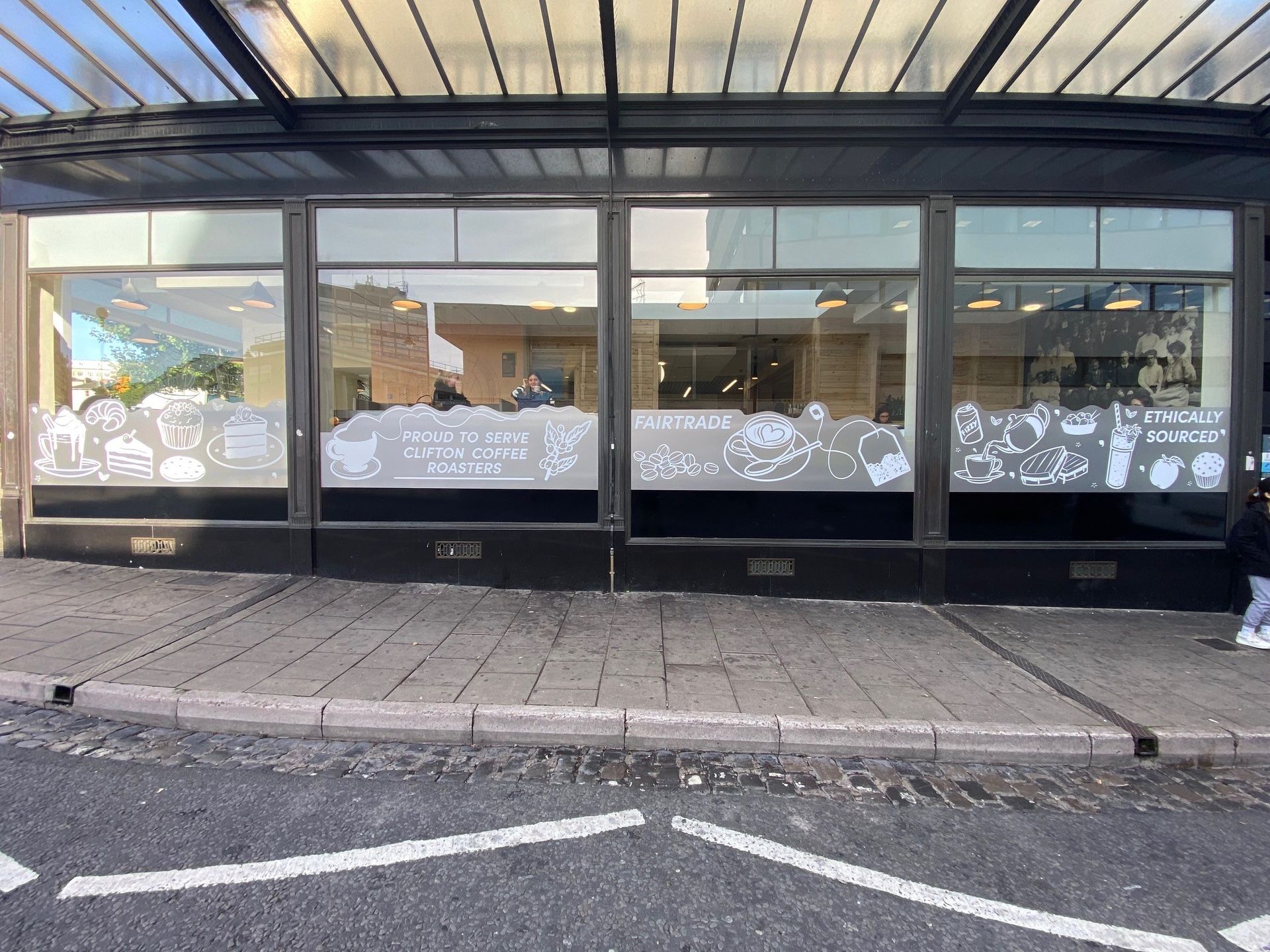 A person is walking in front of a building with a lot of windows.