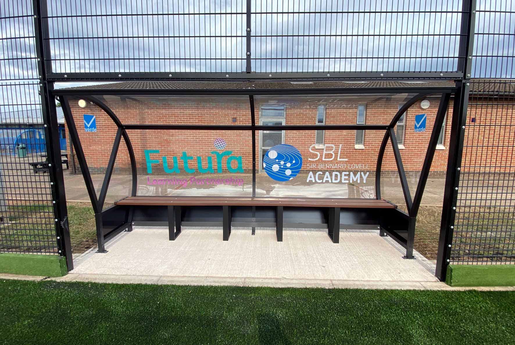 A shelter with a bench in front of a building that says futura academy.