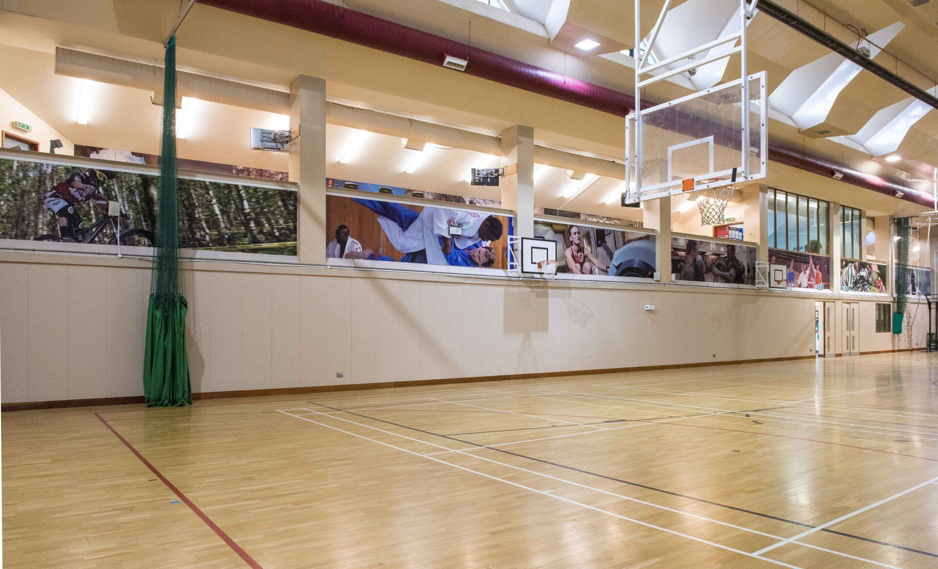 An empty basketball court with a basketball hoop hanging from the ceiling.