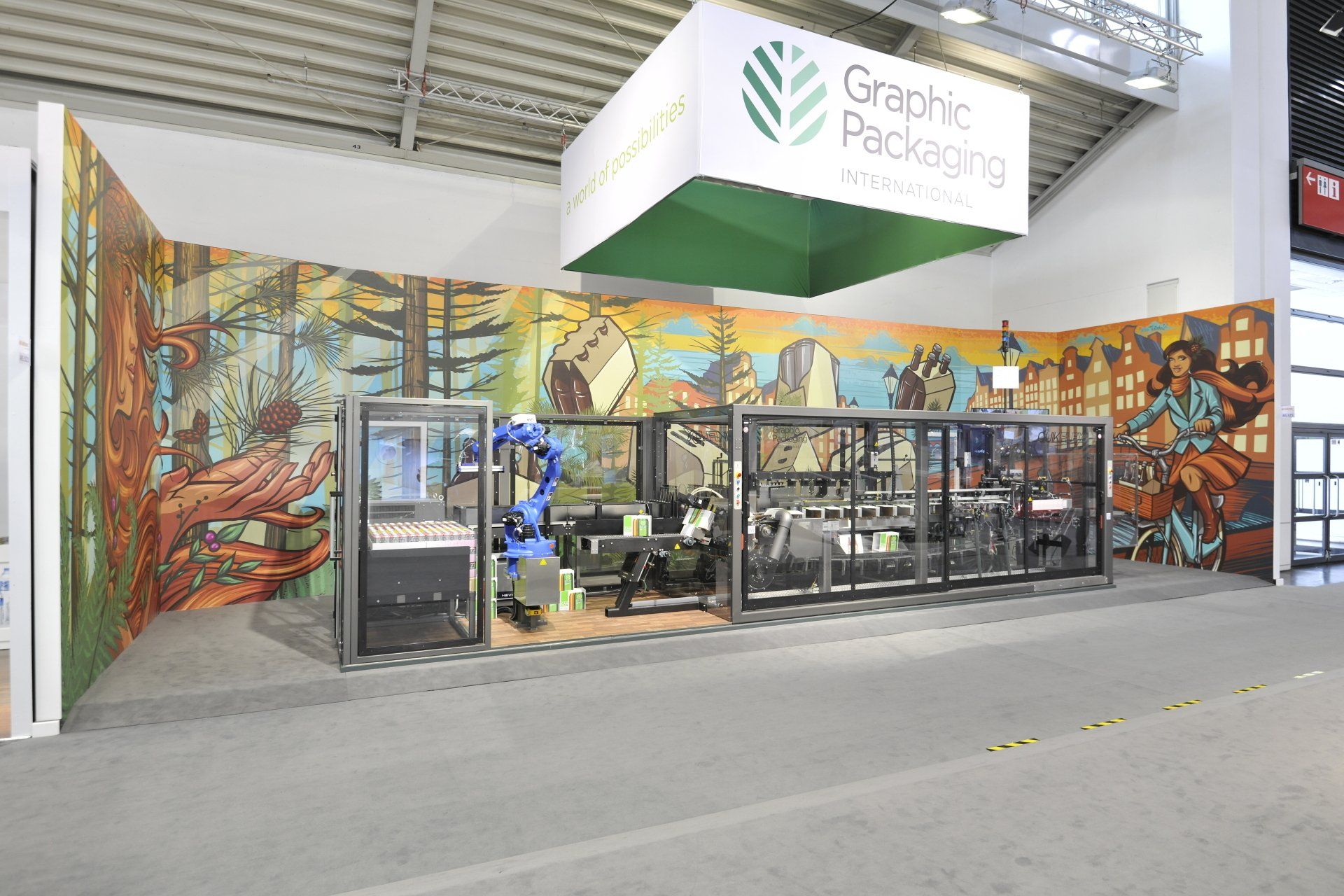 A graphic packaging booth with a robotic arm and a mural on the wall.