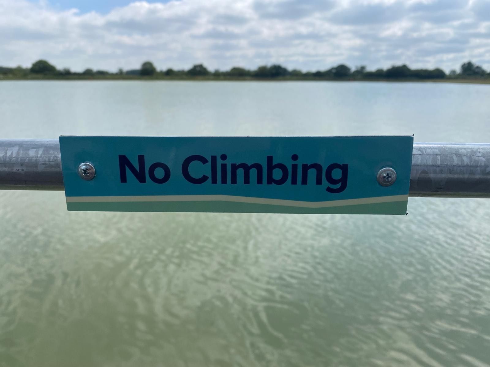 N3 Display Graphics | A no climbing sign is on a railing overlooking a lake.