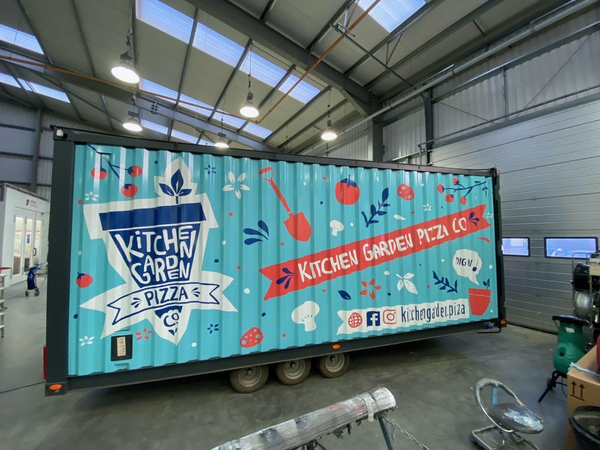 A kitchen garden pizza truck is parked in a warehouse.