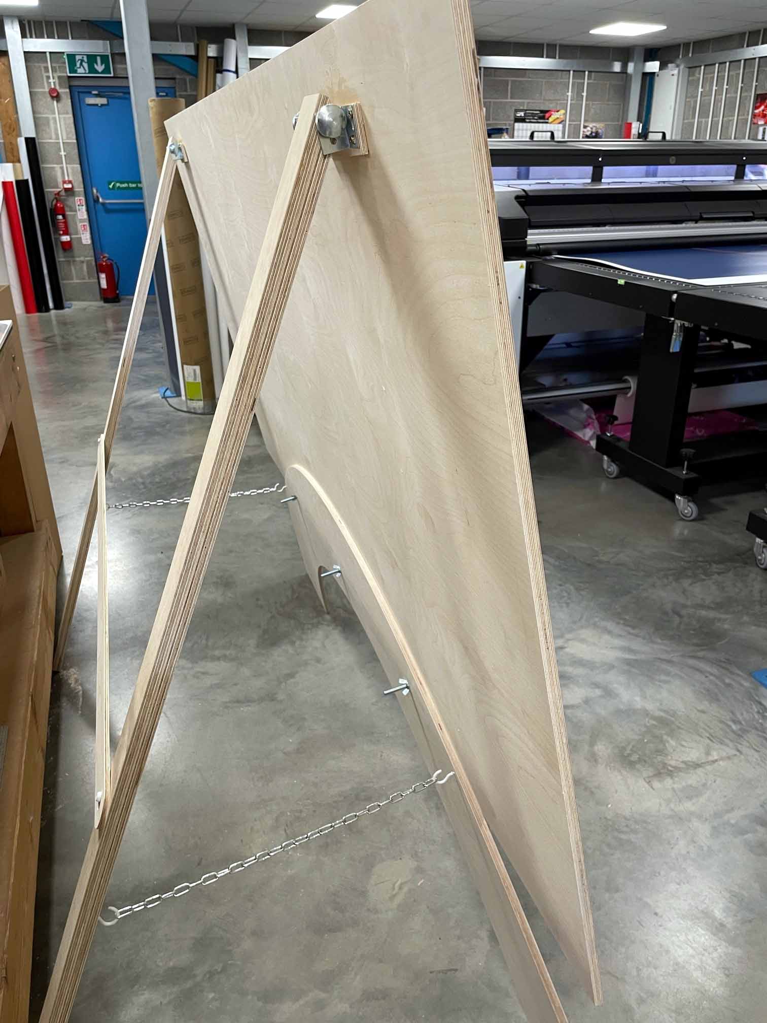 A large piece of wood is sitting on top of a wooden easel in a warehouse.